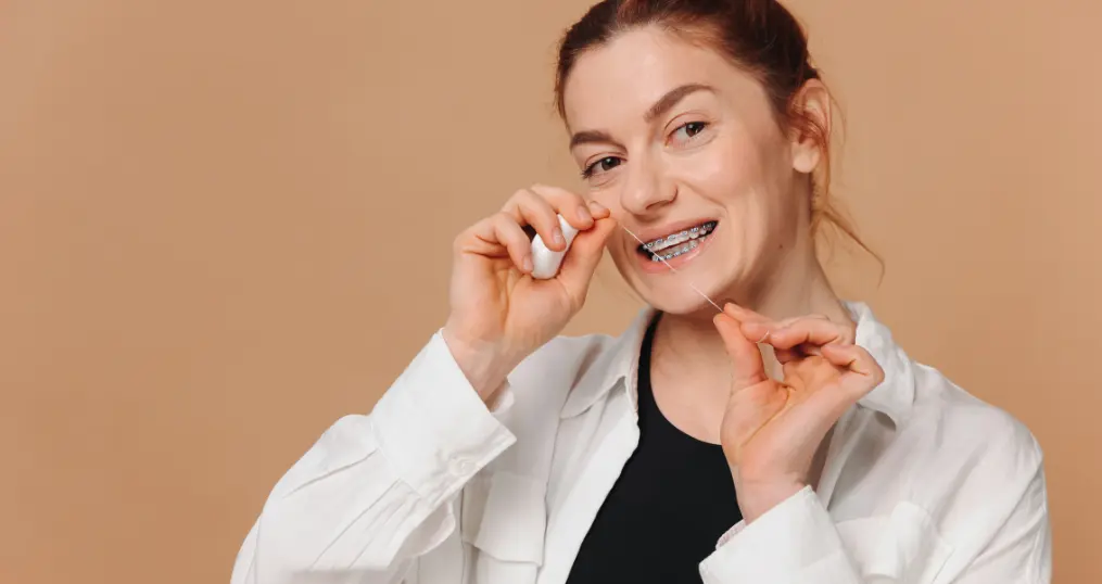 Mulher a usar fio interdentário para higiene oral com aparelho ortodôntico na clínica Blag